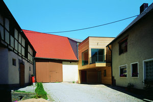  Zum Hof hin öffnet sich der Verbindungsbau im Obergeschoss mit großen Fenstern und einem weit auskragenden Balkon 