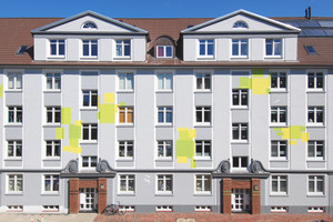  Die straßenseitige Fassade des Wohnblocks zeigt sich in edlen Grautönen, die die Schmuckelemente betonen und fröhlich-aufglockerten Farbflächen 